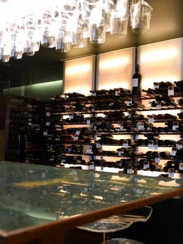 Eleganter Weinkeller mit Weinflaschen an den Wänden und Bartisch