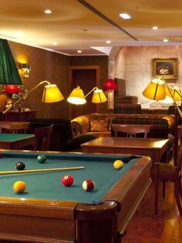 Gemütlicher Billardraum mit Holzvertäfelung und weichen Lampen