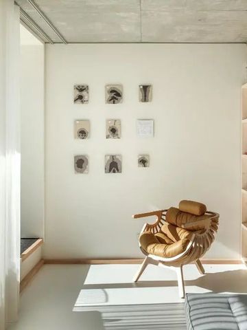 Heller Raum mit Sessel, Kunst an der Wand und einem Bücherregal