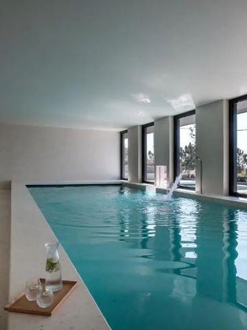 Innenpool mit Liegestühlen und großen Fenstern