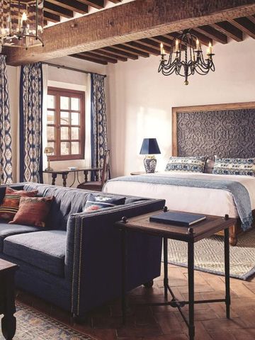 Einladendes Zimmer mit großem Bett, Sofa und Holzbalkendecke.