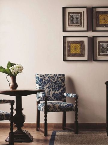 Stilvolle Sitzecke mit kunstvollen Stühlen und hübschem Holztisch vor dekorativen Wandbildern