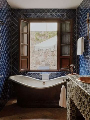 Luxuriöses Badezimmer mit freistehender Wanne und blauen Kacheln