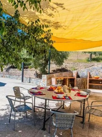 Sonnengeschützter Essbereich im Freien mit runder Tischgruppe und Naturumgebung