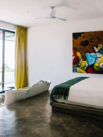 Helles Zimmer mit farbenfrohem Kunstwerk und Terrasse mit Meerblick