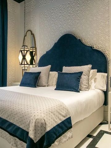 Elegantes Hotelzimmer mit blauem Kopfteil und dekorativen Spiegeln