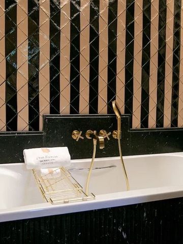 Luxuriöse Badewanne mit goldenen Armaturen und edlen Fliesen