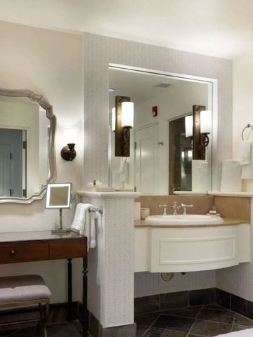 Badezimmer mit großem Spiegel und edlem Waschtisch in warmen Tönen.