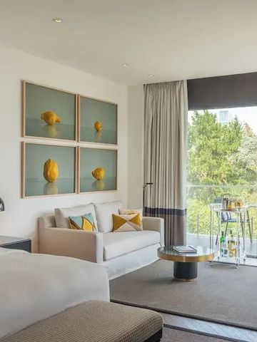 Luxus-Suite mit Wohnzimmerbereich und großen Fenstern mit Gartenblick