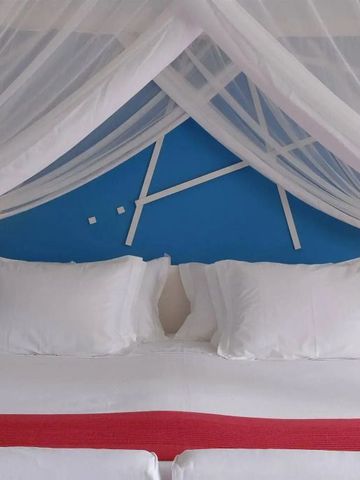 Modernes Doppelbett mit weißen Kissen und Baldachin vor blauer Wand