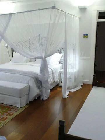 Großzügiges Zimmer mit weißem Baldachinbett und Holzboden