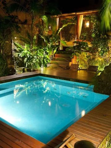 Beleuchteter Pool bei Nacht umgeben von üppigem Grün