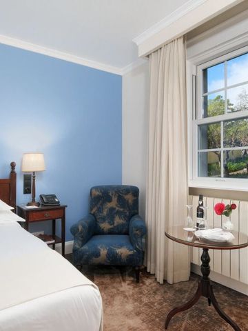 Elegantes Hotelzimmer mit blau gestrichener Wand und Blick in den Garten