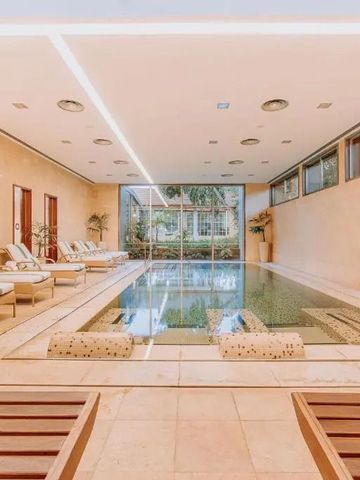 Eleganter Innenpool mit Liegestühlen und großer Fensterfront
