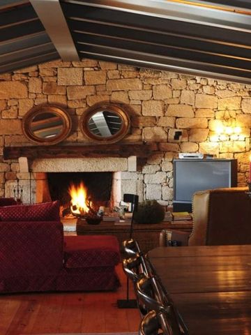 Gemütlicher Raum mit Kamin, Steinwand und eleganten Möbeln im Hotel