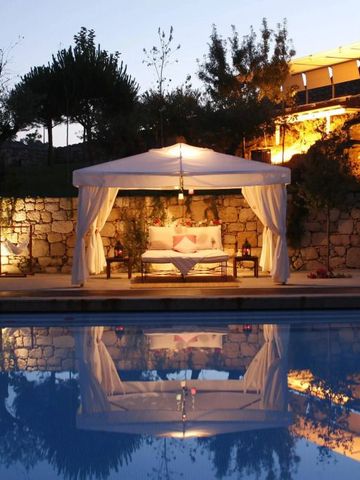 Beleuchteter Pool mit eleganter überdachter Lounge und Liegebereich bei Abenddämmerung