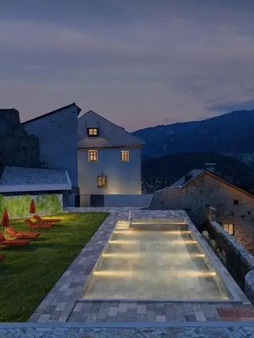 Beleuchteter Außenpool mit Liegen in einer Berglandschaft bei Dämmerung