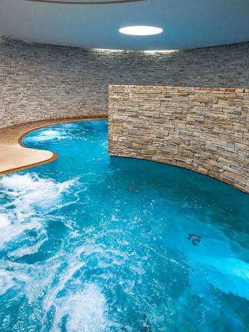 Blaues Wasser im geschwungenen Innenpool mit Natursteinwänden umgeben