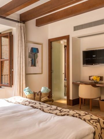Komfortables Schlafzimmer mit offenen Fenstern und Schreibtisch im Castell Son Claret
