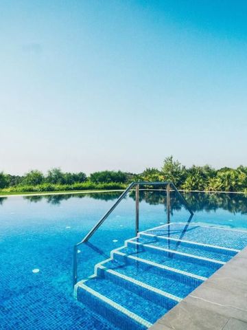 Infinity Pool mit blauen Fliesen und weitem Blick auf die Landschaft bei Sonnenschein