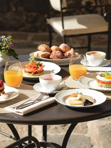 Frühstückstisch mit frischem Orangensaft, Gebäck und Eiern im Freien.