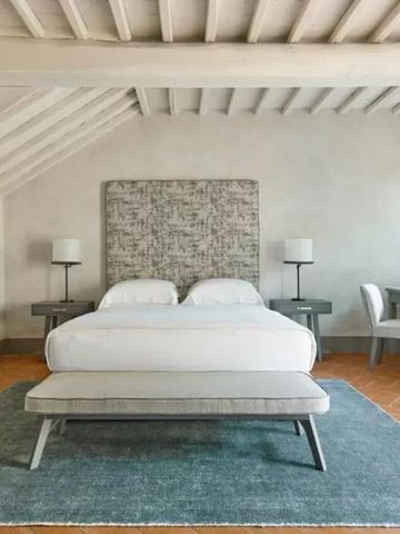 Modernes Schlafzimmer mit rustikalem Charme und Holzbalkendecke im COMO Castello del Nero