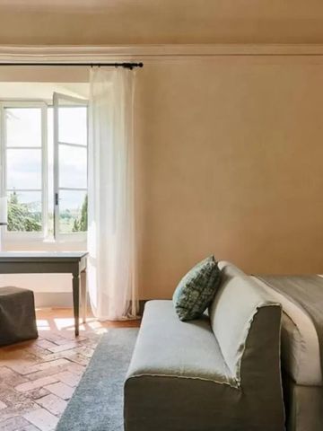 Schlafzimmer mit Sofa und großem Fenster mit Blick ins Grüne