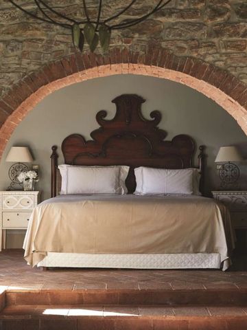 Luxuriöses Schlafzimmer mit gewölbtem Steinbogen und antikem Holzbettrahmen