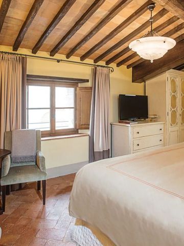 Gemütliches Zimmer mit Holzbalkendecke und moderner Ausstattung im Castello di Casole