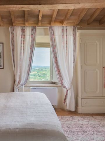 Zimmer mit Holzbalkendecke und Fenster mit Blick auf die toskanische Landschaft