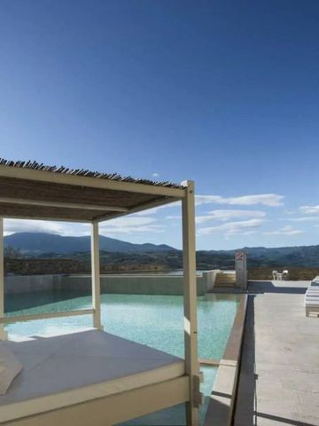 Infinity-Pool mit Liegen und Pavillon, umgeben von beeindruckender Berglandschaft