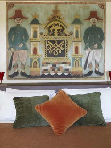 Bett mit Zierkissen und traditionellem Wandgemälde im Hintergrund