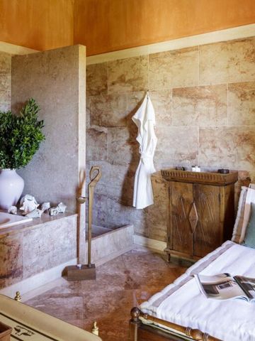 Luxuriöses Badezimmer mit Steinwänden und dekorativem Pflanzenarrangement.