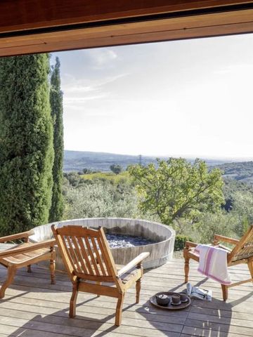 Terrasse mit Stühlen und Whirlpool, umgeben von Natur und weiter Landschaft.