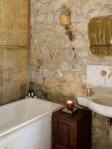 Rustikales Badezimmer mit Steinwänden und antiken Armaturen.