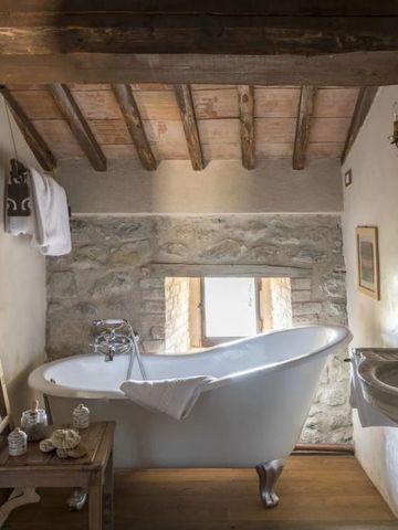 Freistehende Badewanne im Badezimmer mit Holzelementen und Steinwand.