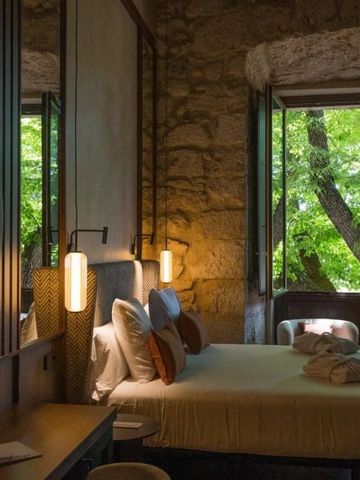 Elegantes Hotelzimmer mit Steinwänden und großem Fenster mit Blick auf Bäume