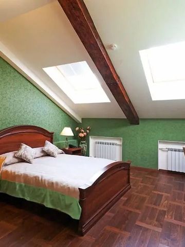 Geräumiges Zimmer mit Holzbalken und großem Bett unter Dachfenstern