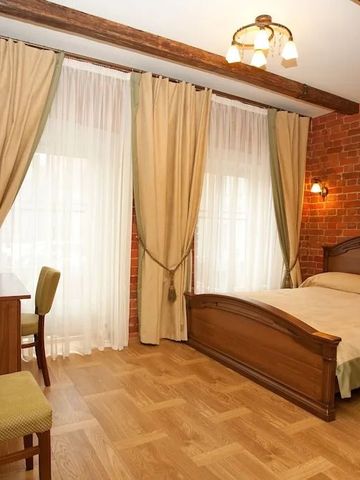 Gemütliches Hotelzimmer mit Holzboden, Backsteinwand und großen Fenstern.