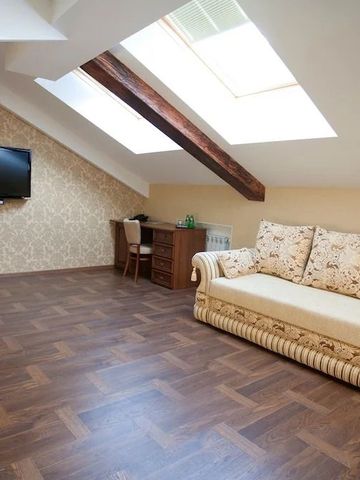 Dachzimmer mit gemütlichem Sofa und Dachfenstern, eleganter Holzboden