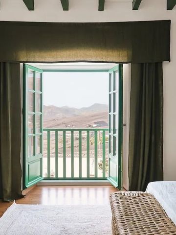 Offenes Fenster mit Blick auf die Landschaft und grüne Vorhänge