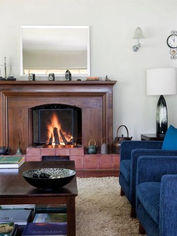 Gemütliches Wohnzimmer mit Kamin und blauen Sesseln in traditionellem Stil