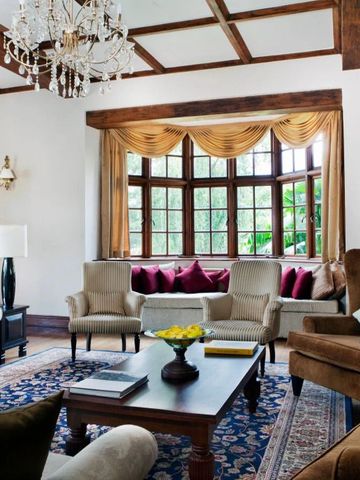 Luxuriöser Salon mit Kronleuchter und großen Fenstern mit Gartenblick