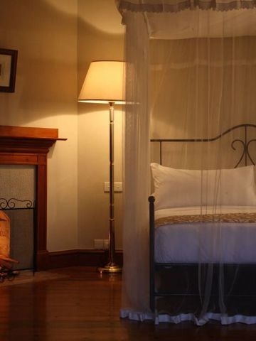 Gemütliches Schlafzimmer mit Kamin und Himmelbett in warmem Licht