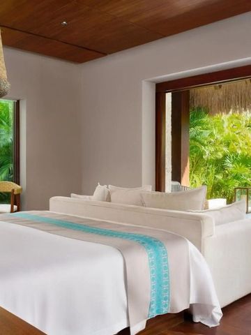 Luxuriöse Suite mit großem Bett und Blick auf tropischen Garten