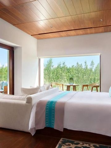 Luxuriöse Suite mit großem Bett und Blick auf den tropischen Garten.