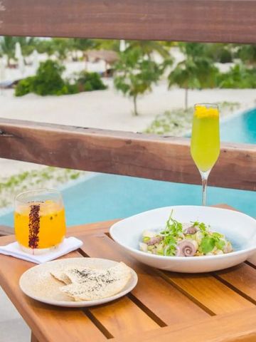 Terrasse mit Poolblick und Getränken vor tropischer Kulisse.