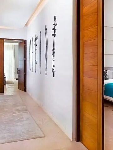 Flur mit modernen Kunstwerken führt zum luxuriösen Schlafzimmer mit Holzakzenten.