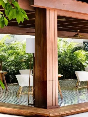 Elegante Outdoor-Terrasse mit Holzelementen und weißer Bestuhlung umgeben von Pflanzen