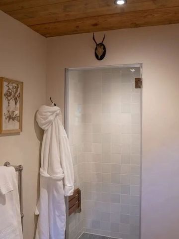Helles Badezimmer mit Dusche, Handtuchhalter und dekorativem Holz